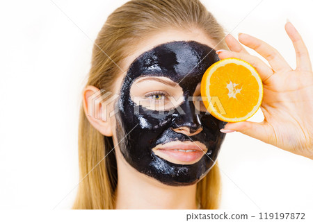 Girl black carbo mask on face holds orange fruit Girl black carbo mask on face holds orange fruit 119197872