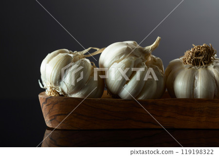 Garlic bulbs in wooden dish on a black background. 119198322