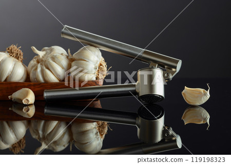 Garlic bulbs and garlic press on a black background. Garlic bulbs and garlic press on a black background. 119198323