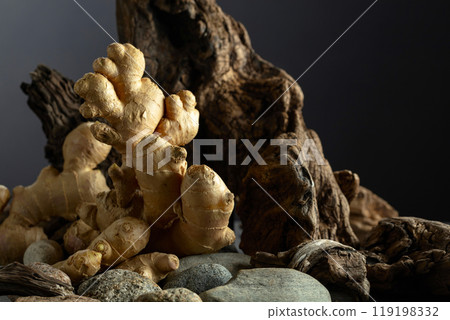 Ginger root with old snags and stones on a black background. Ginger root with old snags and stones on a black background. 119198332