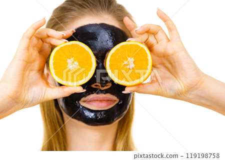 Girl black carbo mask on face holds orange fruit 119198758