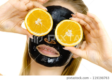 Girl black carbo mask on face holds orange fruit 119198763