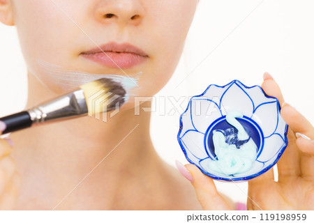 Girl holds bowl with green mud mask 119198959