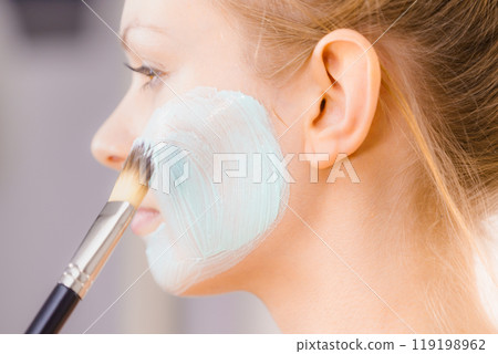 Girl apply green mud mask to face 119198962