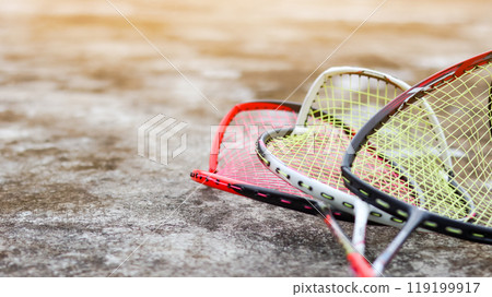 Broken badminton rackets lying on a dark surface, conveying the idea that sports and exercise are better alternatives to violence in society, promoting peace and healthy living. Broken badminton rackets lying on a dark surface, conveying the idea that sports and exercise are better alternatives to violence in society, promoting peace and healthy living. 119199917
