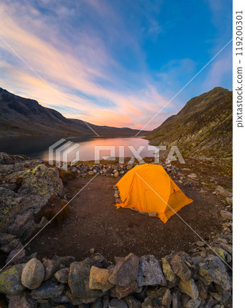 Orange Tent, Lake and Mountains at Sunset. Wild Camping in Jotunheimen National Park. Norway 119200301