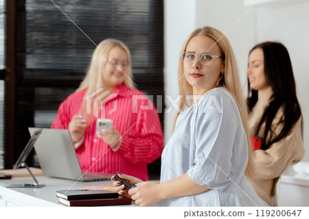 Casual portrait of three women working in the office near a laptop Casual portrait of three women working in the office near a laptop 119200647