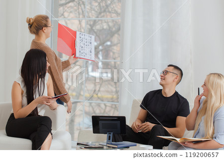 A group of people are sitting around a table in a working environment. 119200657