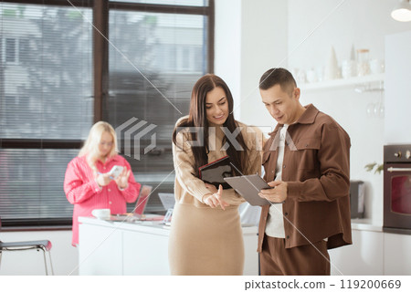 Man and a woman are looking at a tablet in the office break room Man and a woman are looking at a tablet in the office break room 119200669
