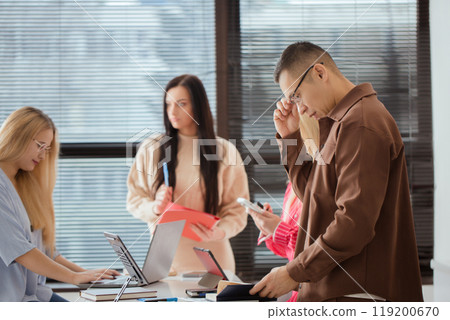 Group of people are sitting around a table with laptops Group of people are sitting around a table with laptops 119200670