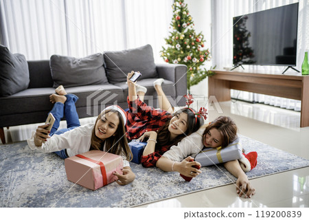 young women using handphone taking picture christmas young women using handphone taking picture christmas 119200839