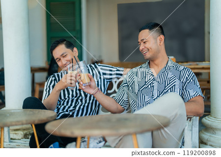 Two Friends Enjoying Refreshing Drinks at a Relaxing Outdoor Caf Two Friends Enjoying Refreshing Drinks at a Relaxing Outdoor Caf 119200898