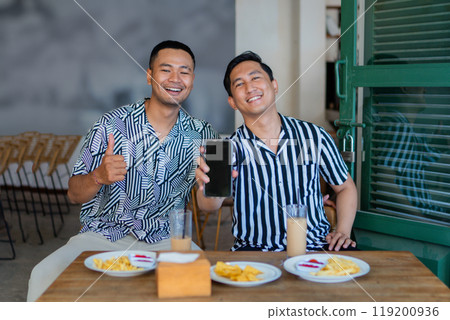 Two friends are enjoying a meal and drinks together at a local restaurant Two friends are enjoying a meal and drinks together at a local restaurant 119200936