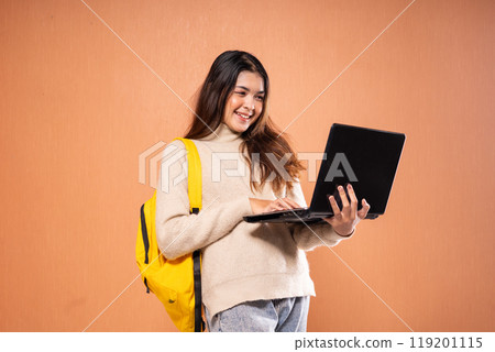 A Cheerful Student with a Laptop and Backpack Poses Against a Colorful Background A Cheerful Student with a Laptop and Backpack Poses Against a Colorful Background 119201115
