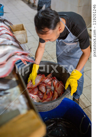 Fish Processing in Market A Worker Skillfully Handling Fresh Catch Effectively 119201246