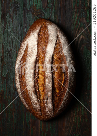 Baked rye homemade bread with malt, oval shape, sprinkled with flour on a wooden background. Baked rye homemade bread with malt, oval shape, sprinkled with flour on a wooden background. 119201269