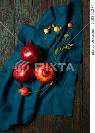 Ripe red pomegranates on a linen napkin on a wooden table Ripe red pomegranates on a linen napkin on a wooden table 119201274