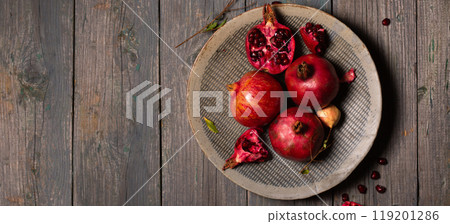 Ripe juicy pomegranates whole and open in a ceramic gray plate on a gray wooden background, banner Ripe juicy pomegranates whole and open in a ceramic gray plate on a gray wooden background, banner 119201286