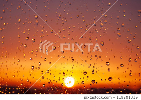 A window with raindrops on it and a sun in the background A window with raindrops on it and a sun in the background 119201319