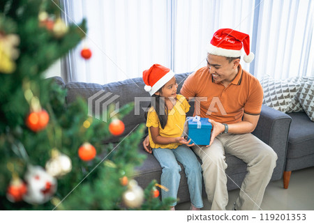 father giving christmas gift to daughter father giving christmas gift to daughter 119201353