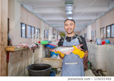 A Happy Fishmonger Proudly Holding a Fresh Catch in a Bustling Seafood Market 119201408