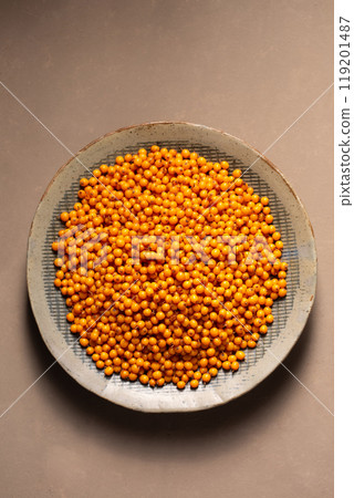 A plate with orange berries stands on a table with a gray napkin, top view A plate with orange berries stands on a table with a gray napkin, top view 119201487