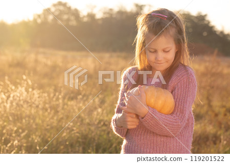 A girl is holding a pumpkin in a field A girl is holding a pumpkin in a field 119201522