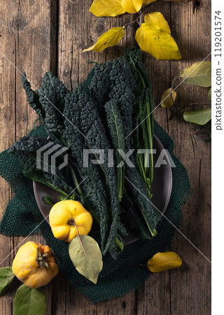 A plate leafy of kale and yellow ripe quince on a wooden table A plate leafy of kale and yellow ripe quince on a wooden table 119201574