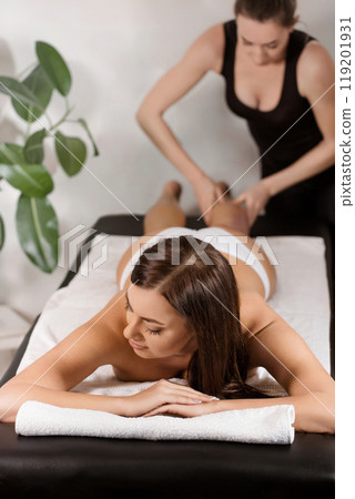 A masseuse gives an anti-cellulite massage to a female patient on a massage table 119201931