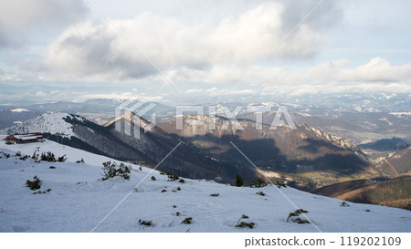 Early winter snowy landscape with mountains and ridgelines with thick clouds casting shadows on it Early winter snowy landscape with mountains and ridgelines with thick clouds casting shadows on it 119202109