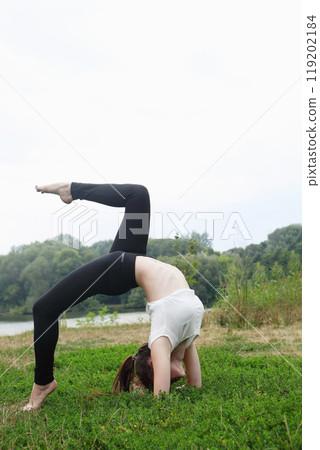 Woman is doing a handstand on the training ground 119202184
