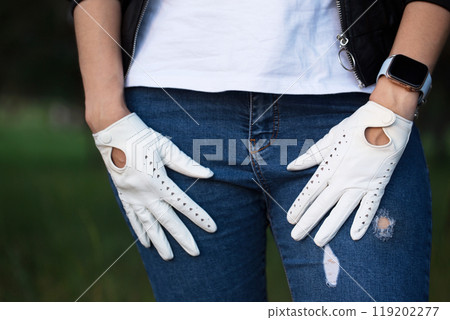 A woman in a brutal black leather jacket and white leather gloves, close-up 119202277