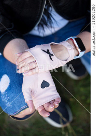 A woman in short pink mittens with a small black heart on the palm, top view 119202290