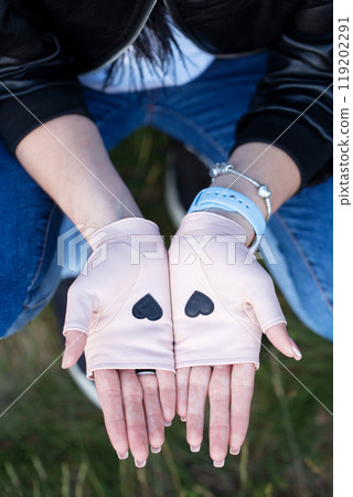 Two open palms in mittens with a small black hearts, top view 119202291