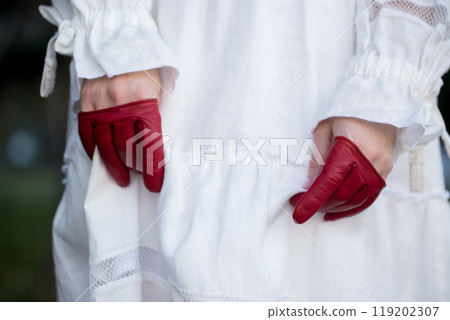 A woman in a white dress and red leather mini mittens, close-up A woman in a white dress and red leather mini mittens, close-up 119202307