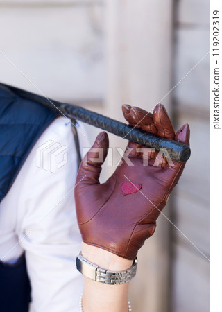 A woman in brown gloves and a whip in her hands 119202319