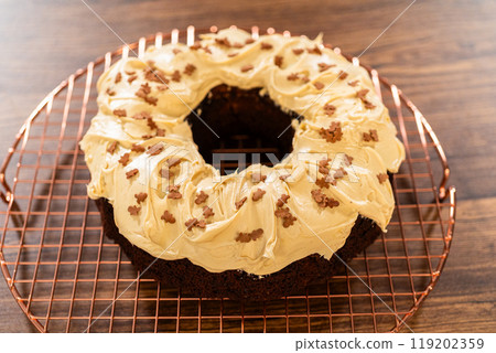 A gingerbread bundt cake being generously frosted with salted caramel frosting and topped with delightful gingerbread sprinkles. A gingerbread bundt cake being generously frosted with salted caramel frosting and topped with delightful gingerbread sprinkles. 119202359