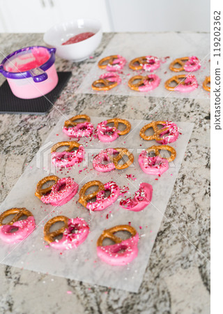 Freshly dipped and still glistening, these crunchy pretzels are lovingly adorned with pink chocolate and a scattering of colorful sprinkles, promising a feast for the senses. Freshly dipped and still glistening, these crunchy pretzels are lovingly adorned with pink chocolate and a scattering of colorful sprinkles, promising a feast for the senses. 119202362