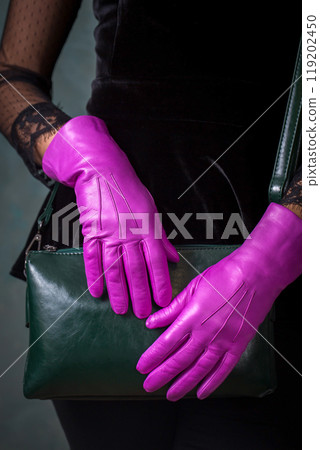 Female hands in bright fuchsia gloves hold a small green handbag Female hands in bright fuchsia gloves hold a small green handbag 119202450