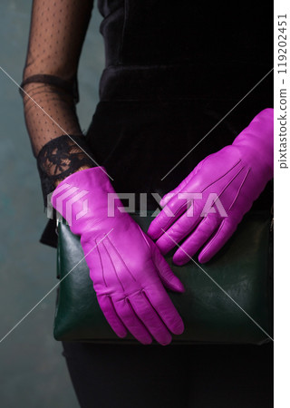 Female hands in bright fuchsia gloves hold a green handbag Female hands in bright fuchsia gloves hold a green handbag 119202451