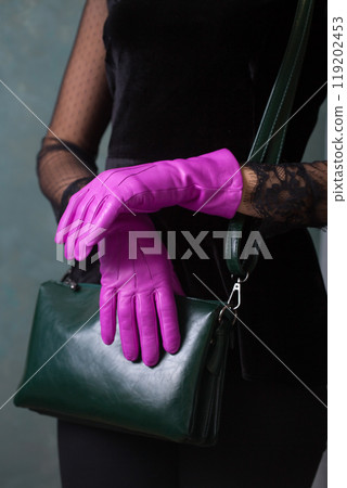 A woman in bright fuchsia gloves hold a small green handbag A woman in bright fuchsia gloves hold a small green handbag 119202453