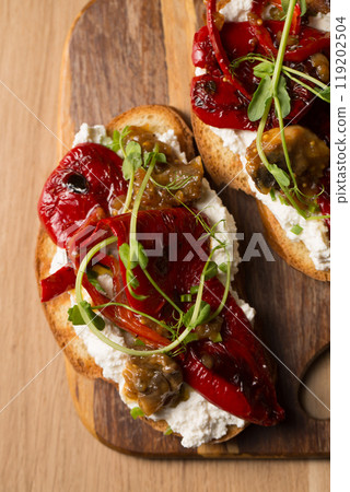 Sandwiches with cheese spread, mushrooms, grilled pepper and microgreen pea pods on a wooden board 119202504