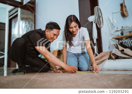 couple of asian production crew measuring the fabric using the measurement tape 119203291