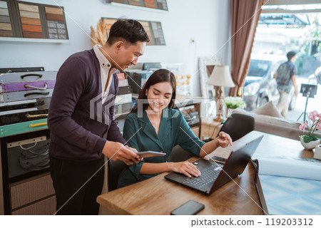 asian shopkeeper pointing on her laptop while looking at the digital tablet asian shopkeeper pointing on her laptop while looking at the digital tablet 119203312