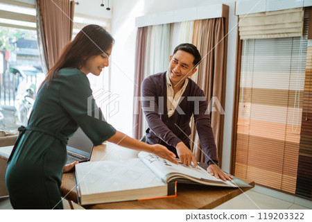 the male customer pointing on the catalogue book to get explanation 119203322