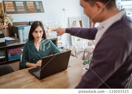 frustrated female shopkeeper glared to the male shop owner that scolding her 119203325