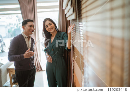 asian male customer paying attention to the beautiful window treatments shopkeeper 119203448
