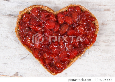 Bread in shape of heart with strawberry jam for breakfast. Rustic background Bread in shape of heart with strawberry jam for breakfast. Rustic background 119203538
