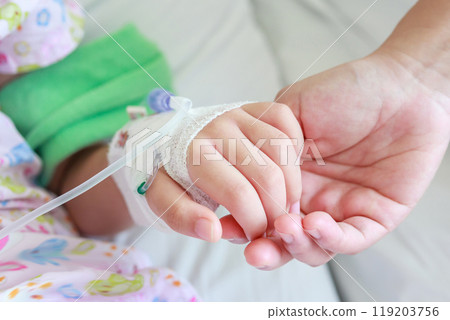 Mother holding child hand with saline IV solution in hospital 119203756
