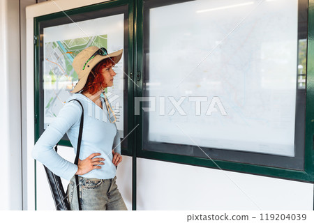 portrait of young red-haired woman, tourist in city, at metro station or train station 119204039